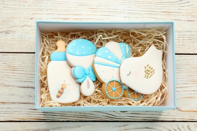 Set of baby shower cookies in gift box on white wooden table, top view