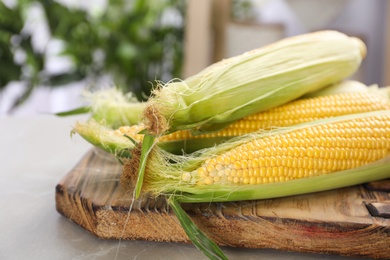 Photo of Tasty sweet corn cobs on wooden board