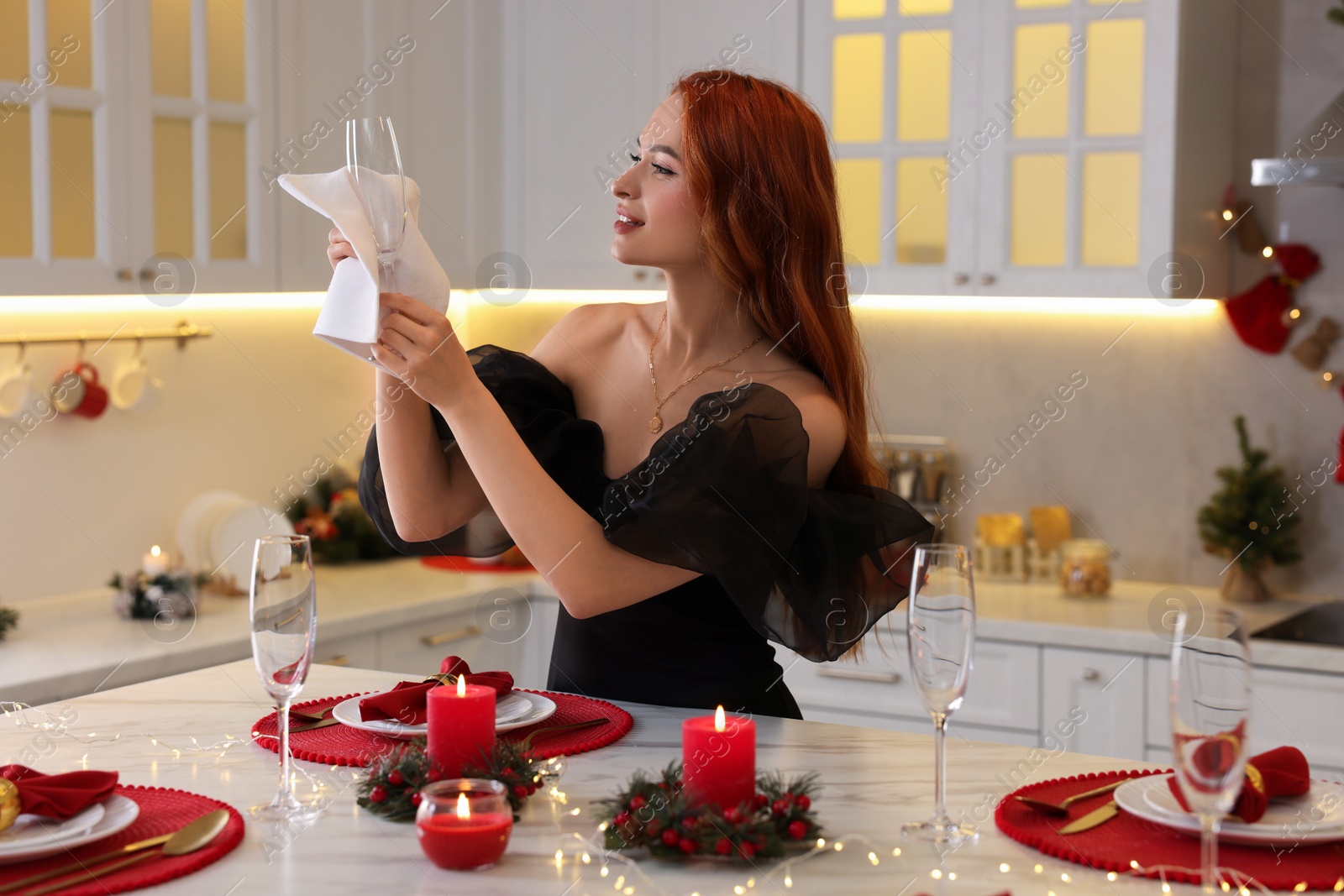 Photo of Beautiful young woman setting table for Christmas celebration in kitchen