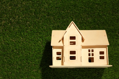 Photo of Wooden house model on green grass, top view. Space for text