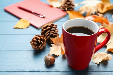 Photo of Cup of hot drink and leaves on blue wooden table. Cozy autumn atmosphere
