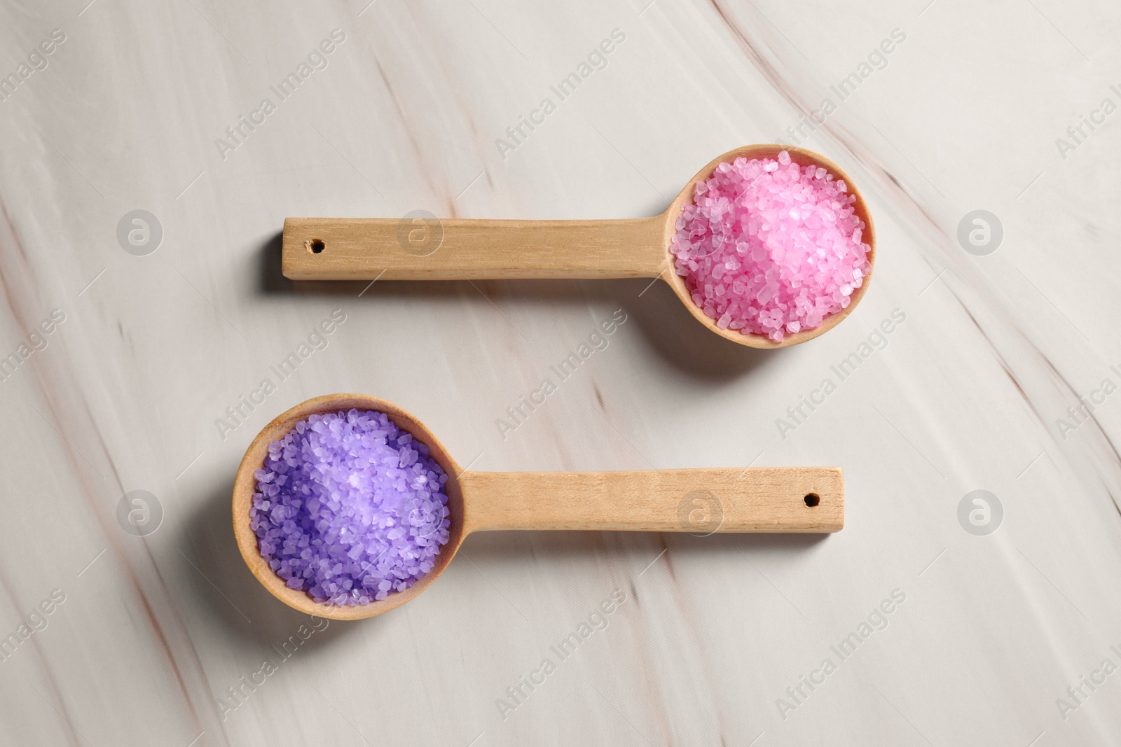 Photo of Spoons with sea salt on wooden table, top view