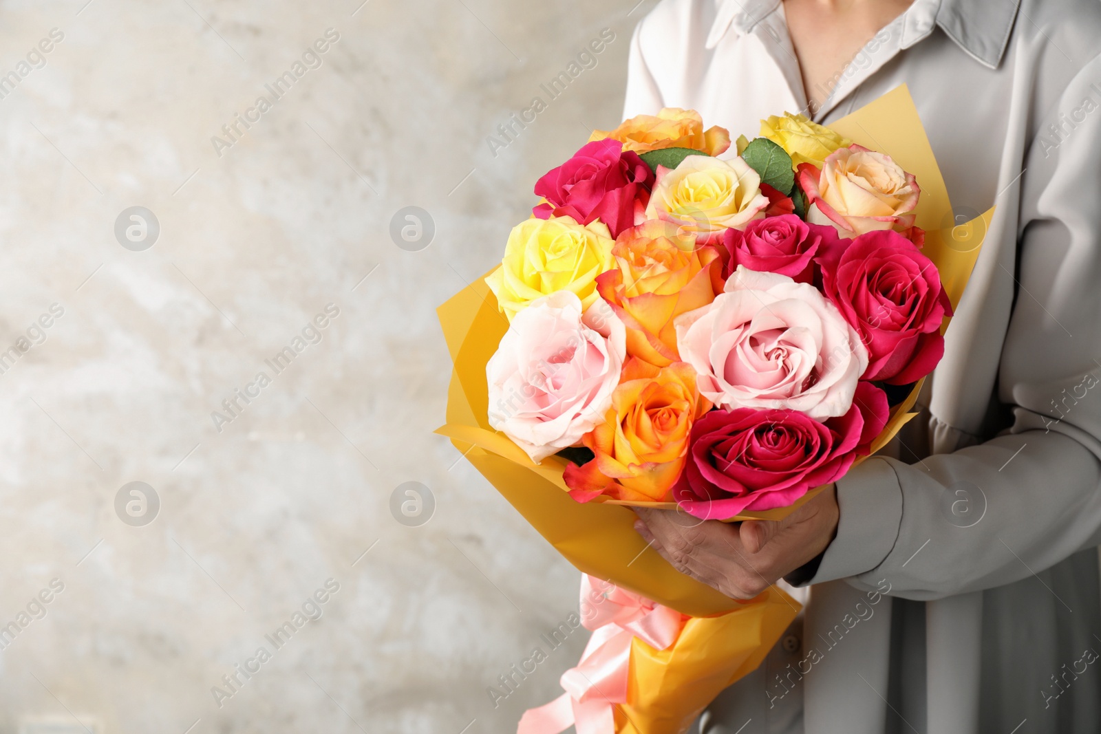 Photo of Woman holding luxury bouquet of fresh roses on beige background, closeup. Space for text