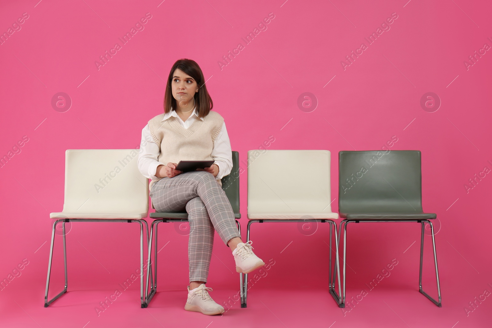 Photo of Young woman with tablet waiting for job interview on pink background