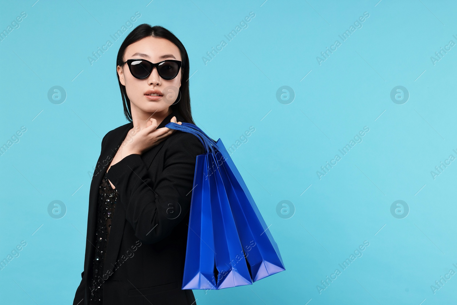 Photo of Beautiful woman with shopping bags on light blue background. Space for text