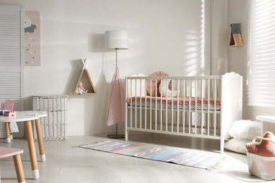 Photo of Cute baby room interior with crib and decor elements