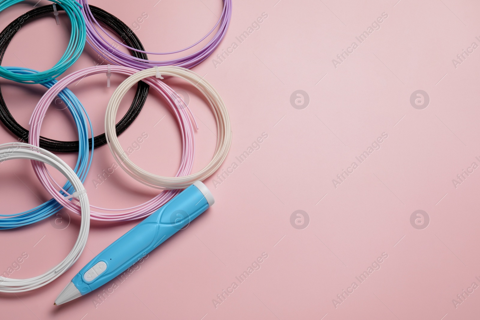 Photo of Stylish 3D pen and colorful plastic filaments on pink background, flat lay. Space for text