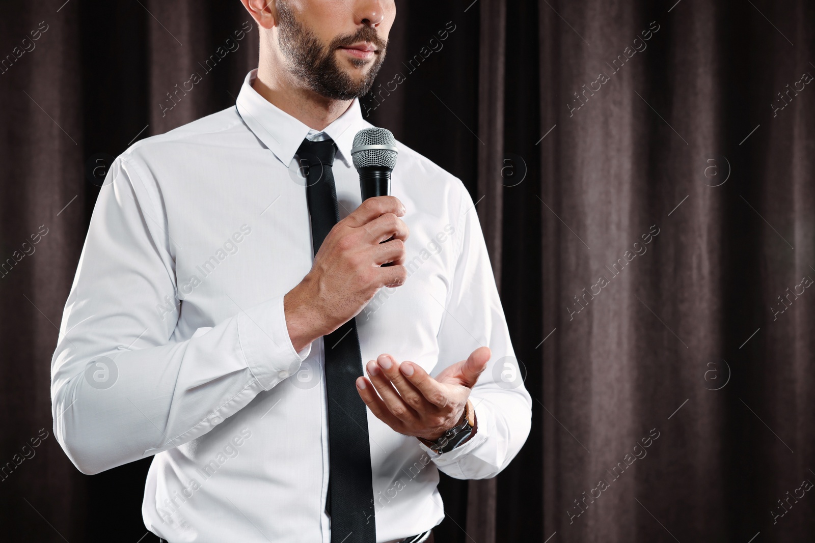 Photo of Motivational speaker with microphone performing on stage, closeup