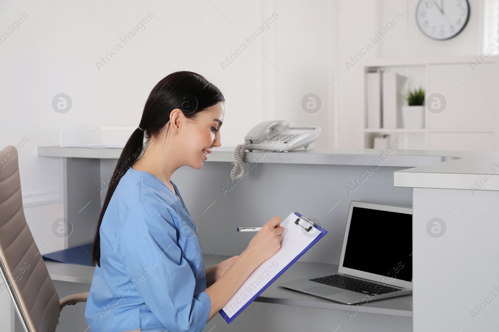 Photo of Receptionist with clipboard at workplace in hospital