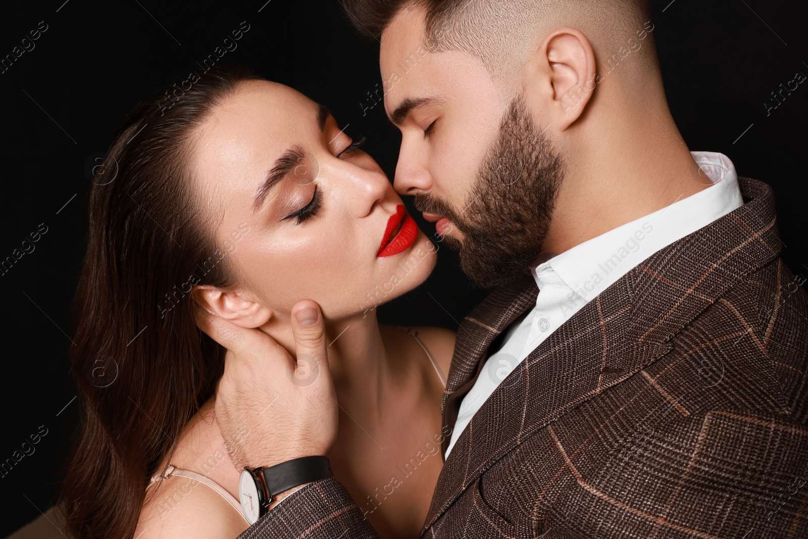 Photo of Handsome bearded man with sexy lady on black background, closeup