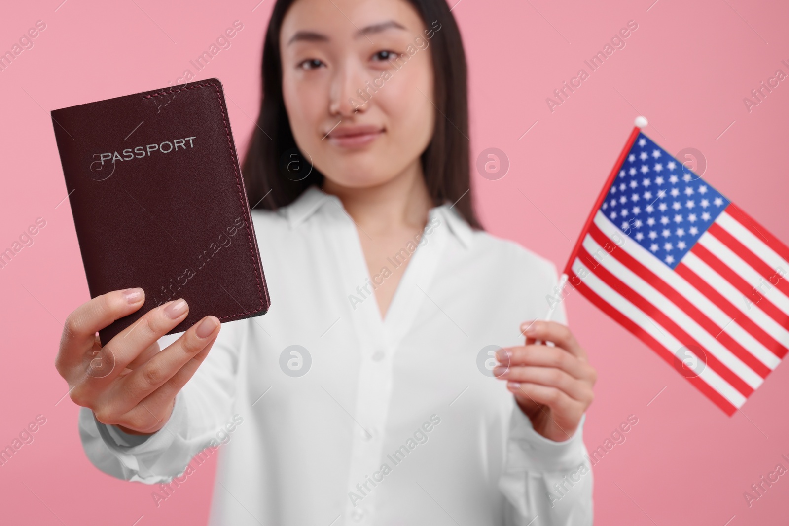 Photo of Immigration to United States of America. Woman with passport and flag on pink background, selective focus