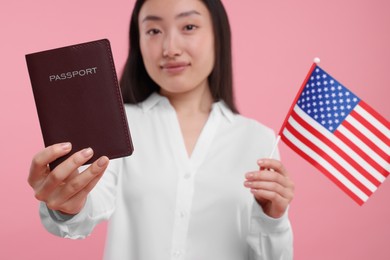 Immigration to United States of America. Woman with passport and flag on pink background, selective focus