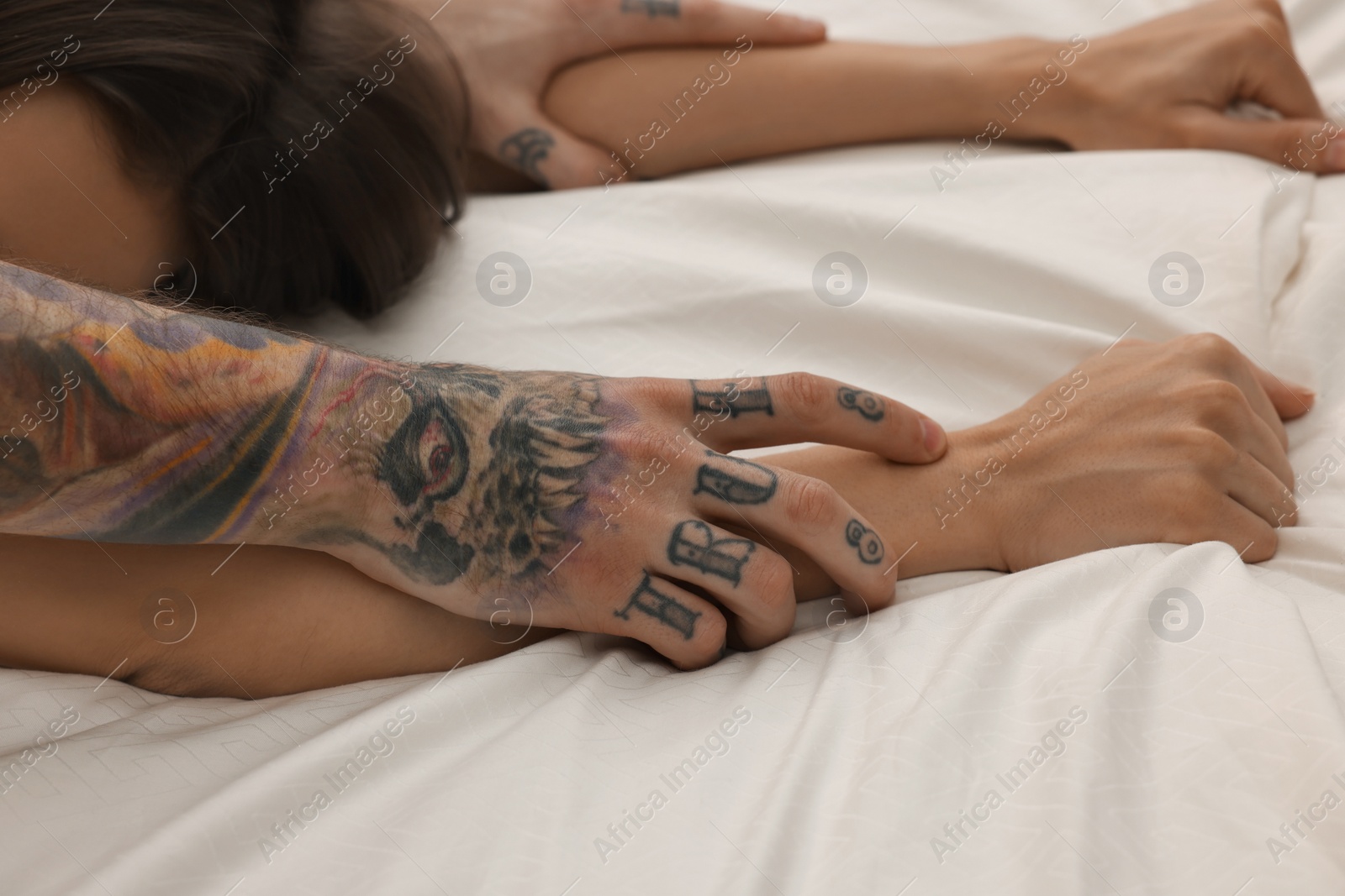 Photo of Passionate couple having sex on bed, closeup of hands