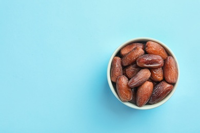 Photo of Bowl with sweet dried date fruits on color background, top view. Space for text