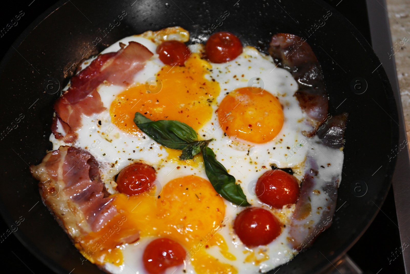 Photo of Tasty eggs with tomatoes and bacon in frying pan for breakfast, closeup