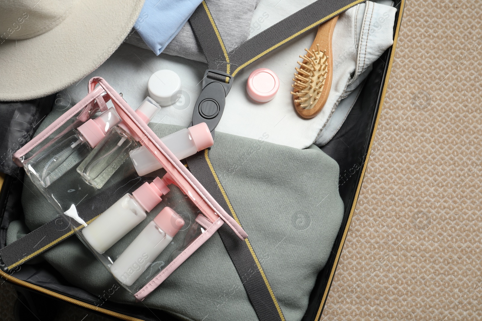 Photo of Plastic bag of cosmetic travel kit in suitcase, top view