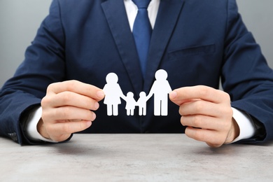 Photo of Man holding cutout paper family at table, closeup. Life insurance concept