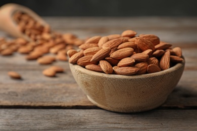 Photo of Tasty organic almond nuts in bowl on table