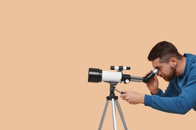 Photo of Astronomer looking at stars through telescope on beige background. Space for text