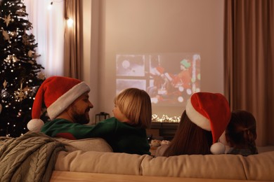 Photo of Family spending time together near video projector in room, back view. Christmas atmosphere