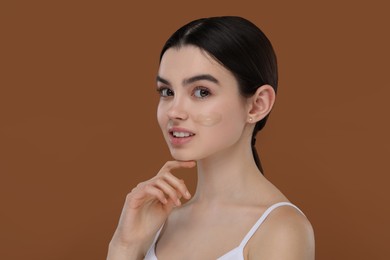 Photo of Teenage girl with swatch of foundation on face against brown background