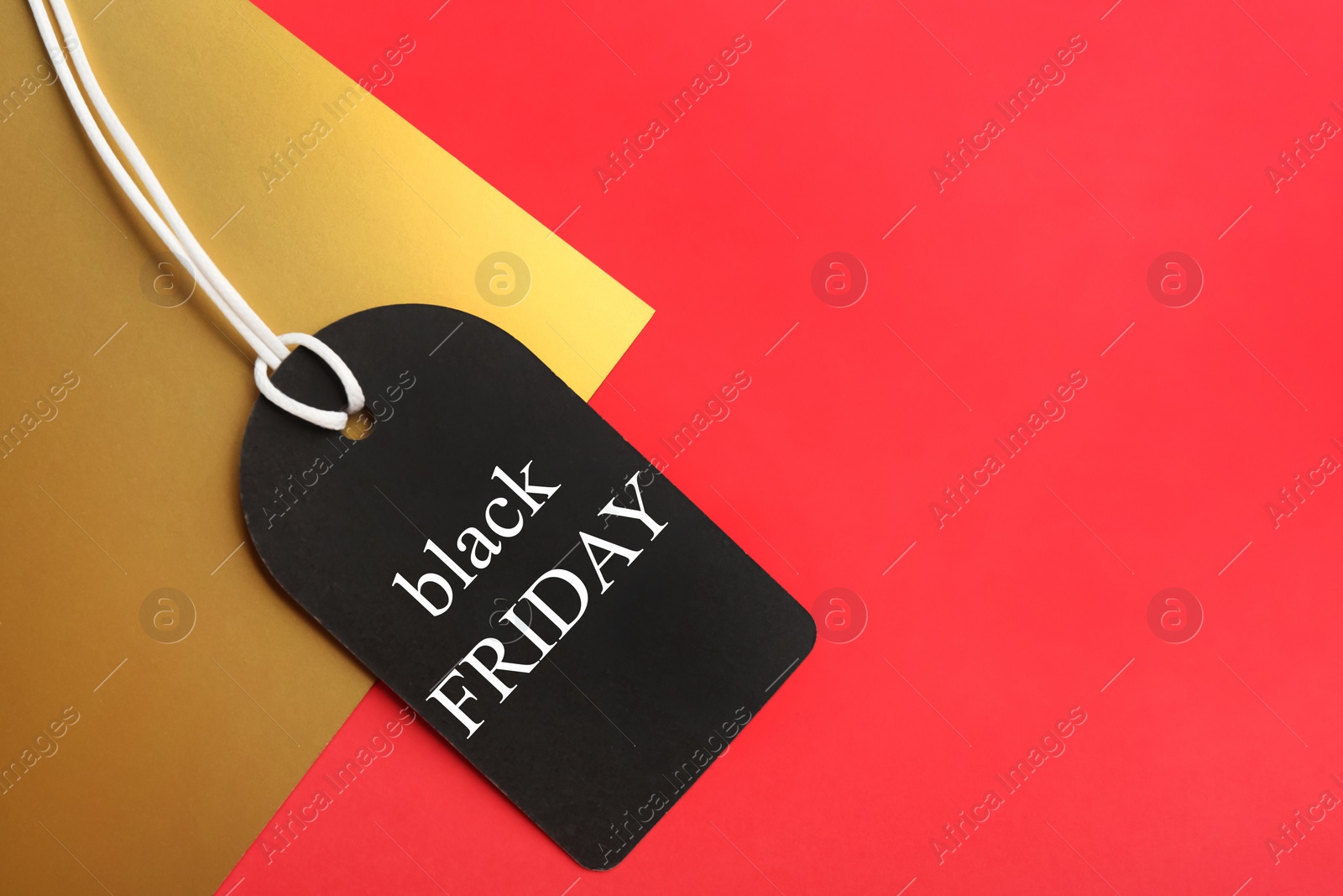Photo of Top view of tag with words BLACK FRIDAY on color background, space for text