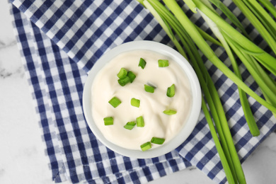 Photo of Fresh sour cream with onion on fabric, flat lay