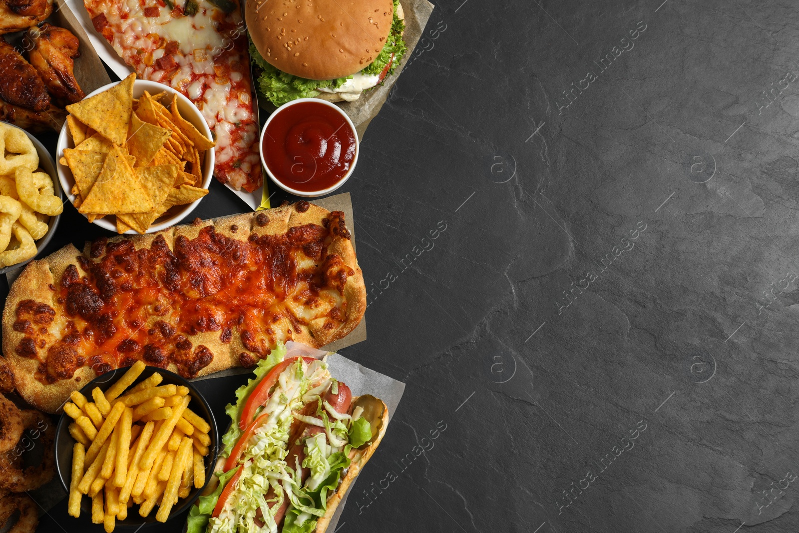 Photo of Burger, pizza and other fast food on black table, flat lay with space for text