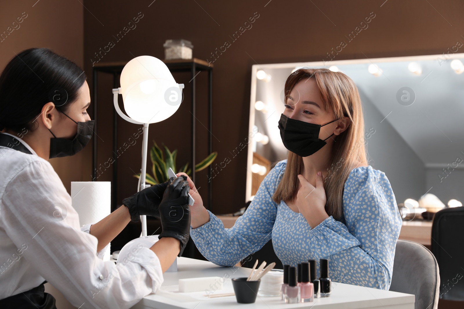 Photo of Professional manicurist working with client in salon. Beauty services during Coronavirus quarantine