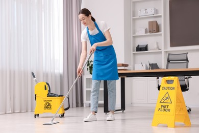 Cleaning service. Woman washing floor with mop in office