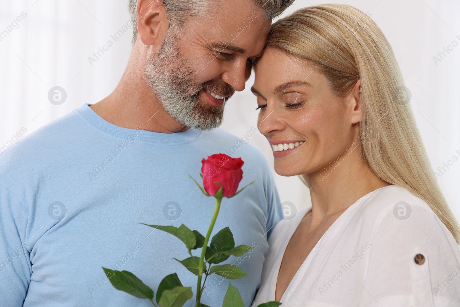 Photo of Happy affectionate couple with red rose at home. Romantic date