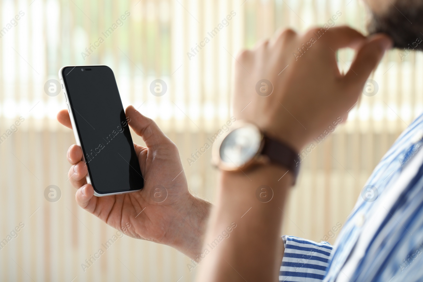 Photo of Man using smartphone near window indoors, closeup view