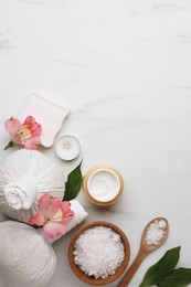 Flat lay composition with spa products and flowers on white marble table. Space for text