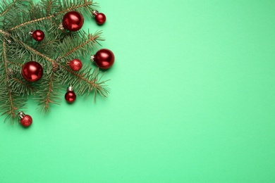 Fir branch with shiny Christmas balls on green background, top view. Space for text