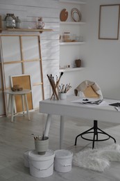 Photo of Modern studio interior with artist's workplace and art supplies