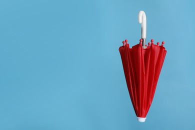 Photo of Closed small red umbrella on light blue background. Space for text