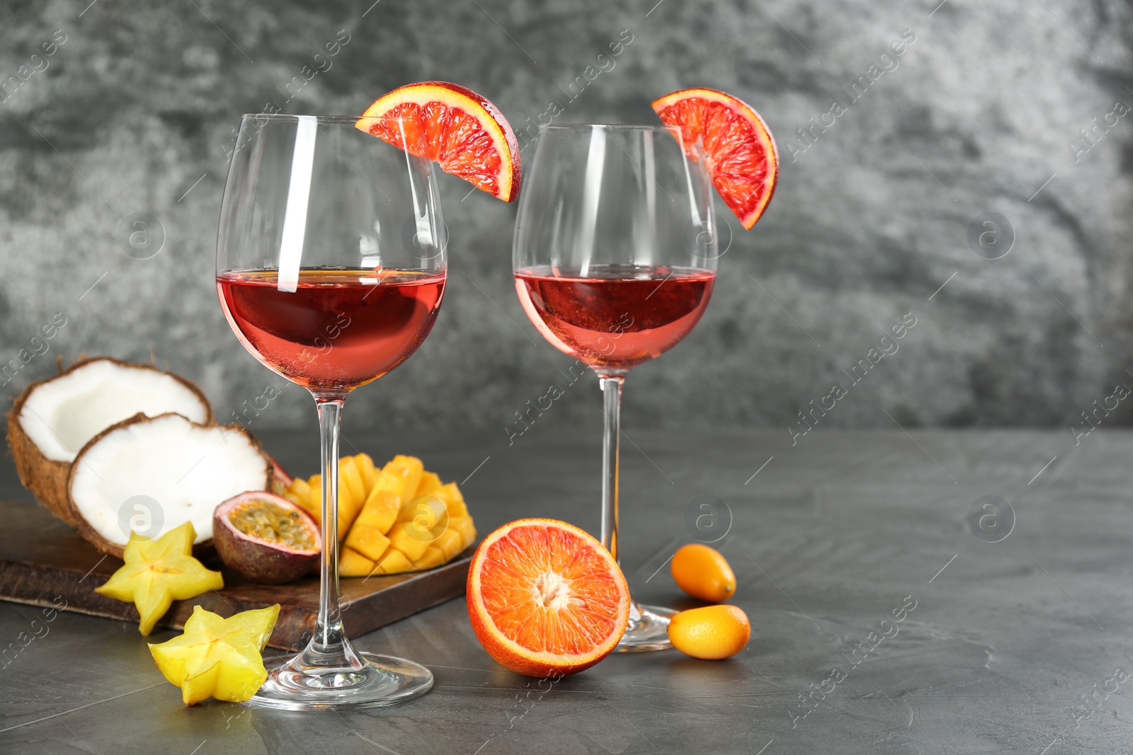 Photo of Delicious exotic fruits and wine on grey table