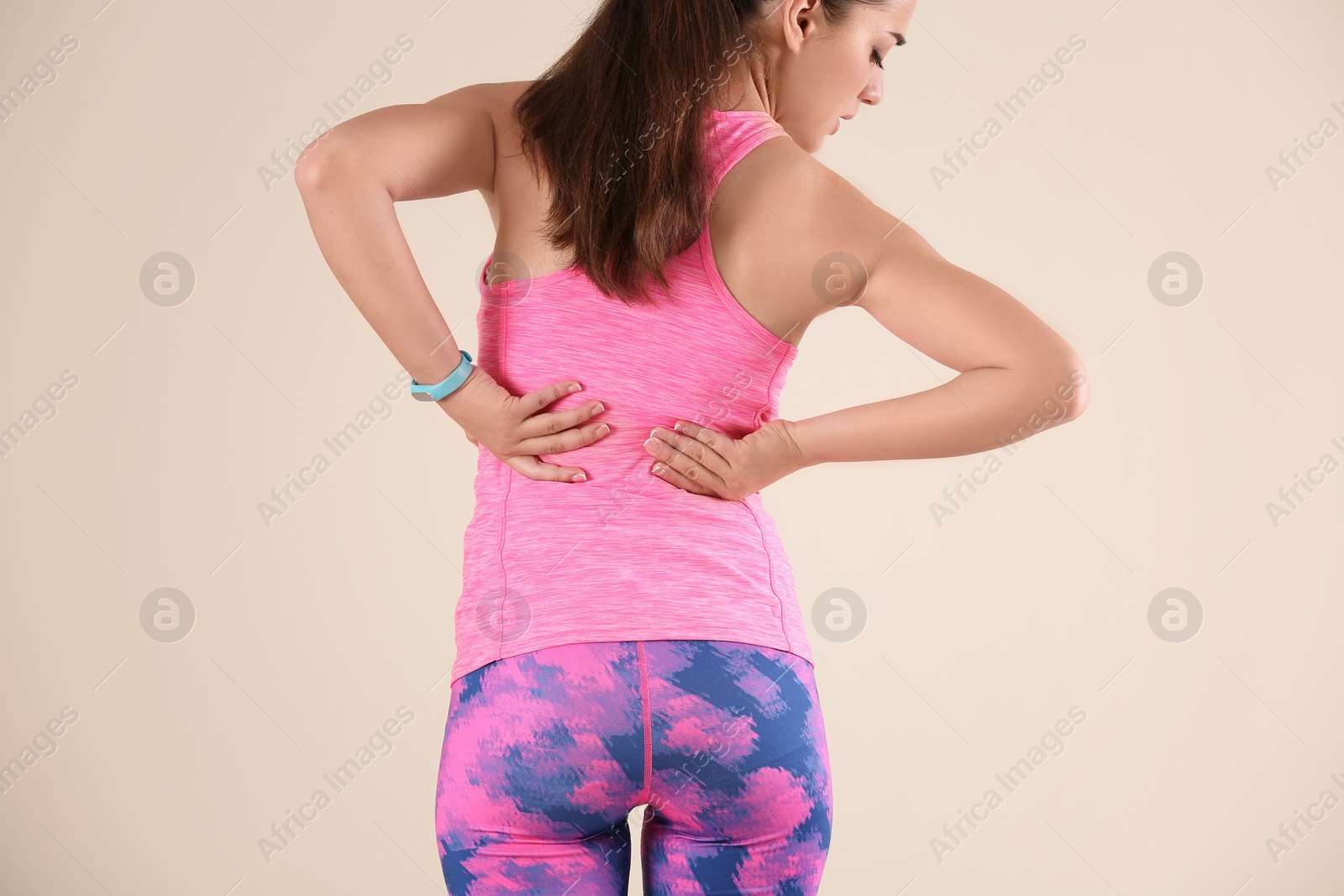 Photo of Woman in sportswear suffering from back pain on light background