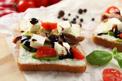 Photo of Delicious sandwiches with anchovies, cheese, tomatoes and sauce on wooden table, closeup