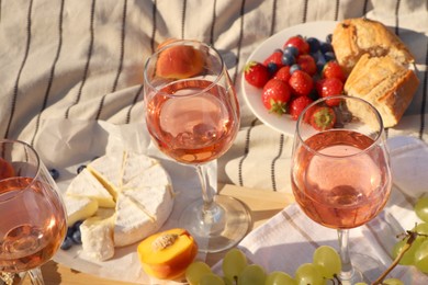 Glasses of delicious rose wine and food on white picnic blanket