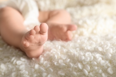 Photo of Little baby with cute feet on soft blanket, closeup. Space for text