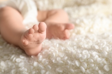 Little baby with cute feet on soft blanket, closeup. Space for text