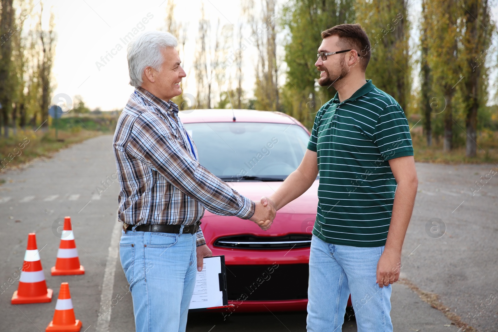 Photo of Happy man shaking hands with senior instructor outdoors. Get driving license