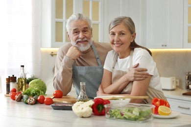 Happy senior couple at table in kitchen