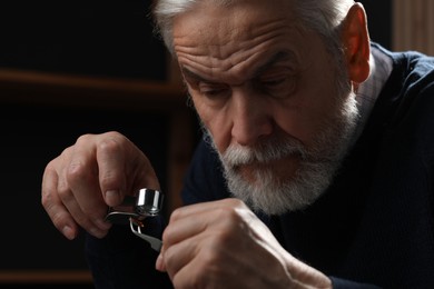 Professional jeweler working with gemstone on dark background, closeup