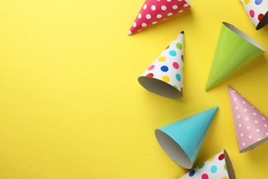 Photo of Beautiful party hats on yellow background, top view. Space for text