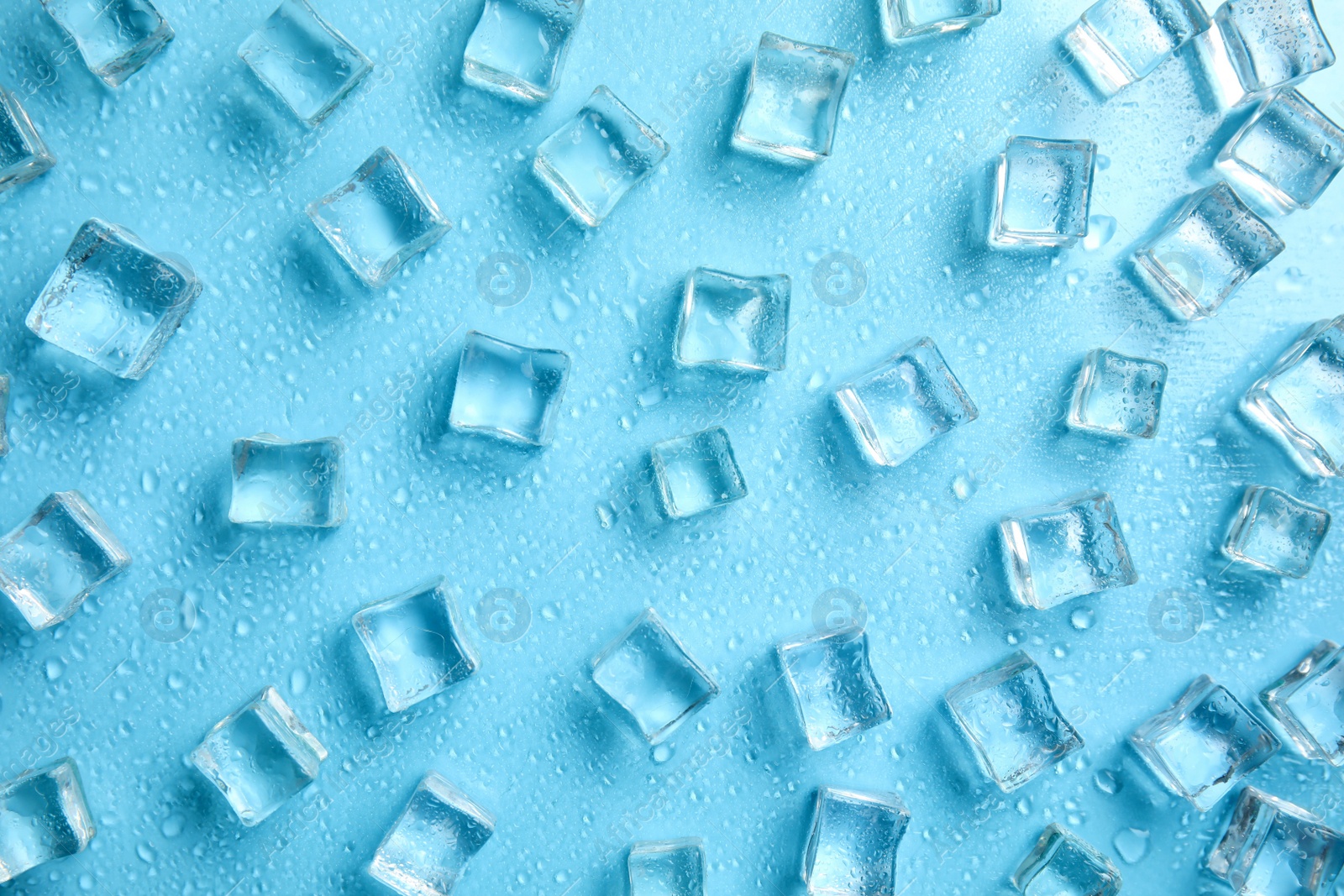 Photo of Cold ice and water drops on turquoise background, flat lay. Ingredient for refreshing drink