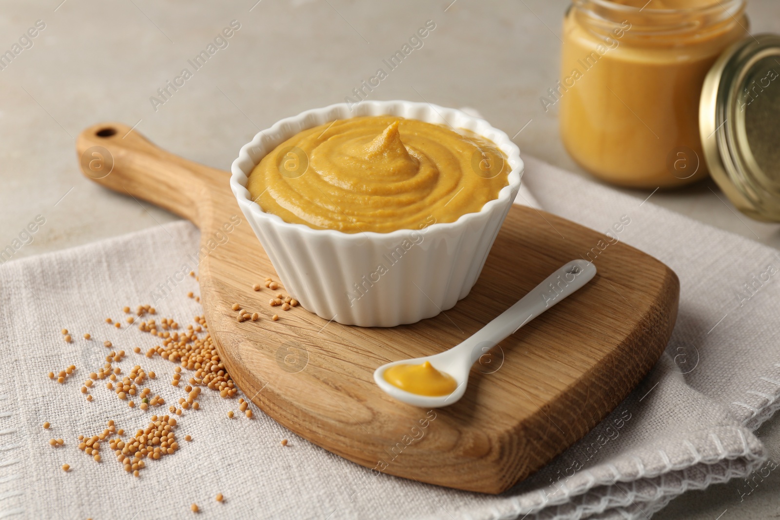 Photo of Tasty mustard sauce and dry seeds on light table