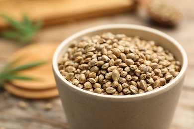 Photo of Organic hemp seeds in bowl on table, closeup