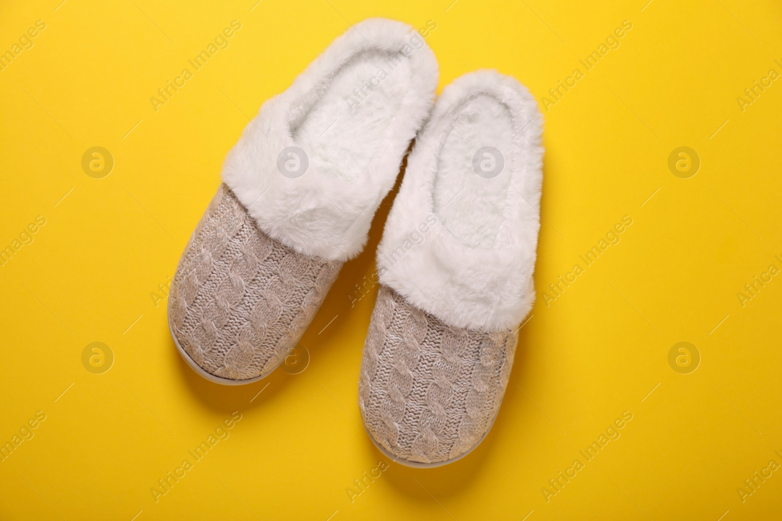 Photo of Pair of beautiful soft slippers on yellow background, top view